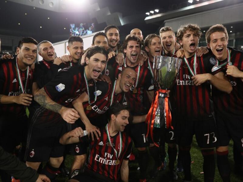 AC Milan's players pose with the trophy after winning against Juventus during the Italian Super Cup final match between AC Milan and Juventus in Doha on December 23, 2016. AC Milan beat Juventus to win the Italian Super Cup in a penalty shootout, the first trophy the Rossoneri have won since 2011. KARIM JAAFAR / AFP