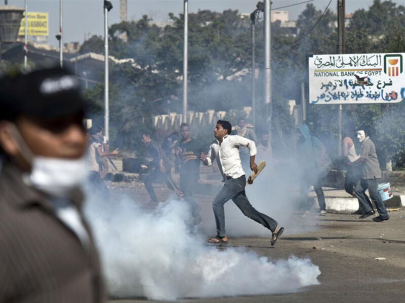 Egyptian students of al-Azhar university run for cover from a tear gas canister fired by riot police during clashes outside their university. [ AFP photo / Khaled Desouki]