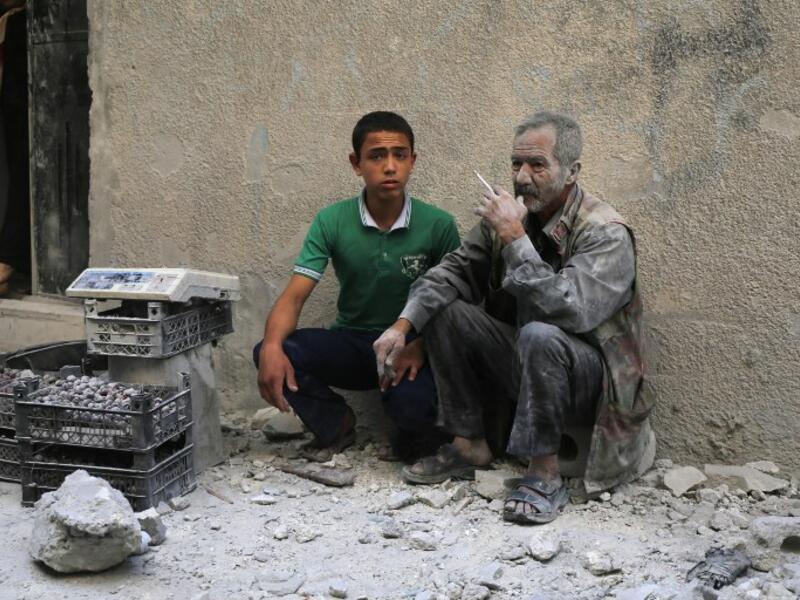A man covered with dust sits on a street following a reported airstrike by Syrian government forces in the rebel-held neighborhood of Sukkari in Aleppo on May 30, 2016. (AFP/Baraa al-Halabi)