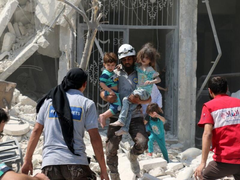 A Syrian rescue worker carries children in the Maadi district of eastern Aleppo after regime aircrafts reportedly dropped explosive-packed barrel bombs on August 27, 2016. (AFP/Ameer Alhalbi)