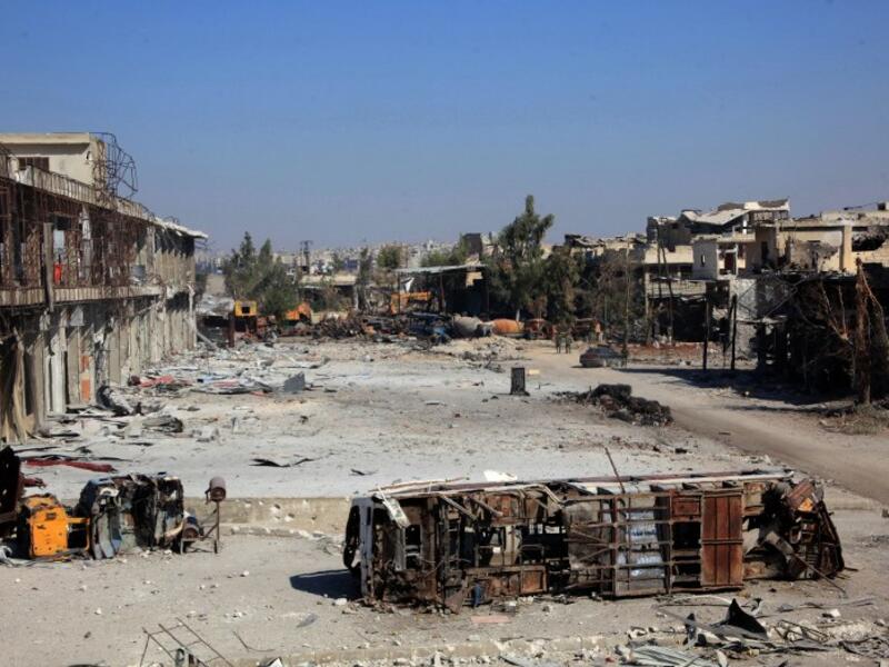 The carcass of a bus litters a bombed-out street in Ramussa on September 9, 2016, after pro-regime fighters took control of the strategically important district on the outskirts of the Syrian city of Aleppo yesterday. (AFP/George Ourfalian)