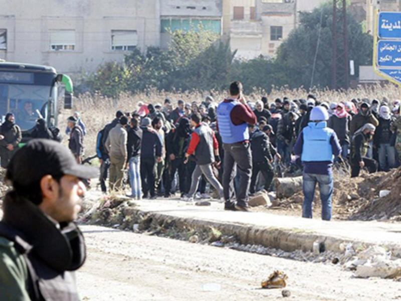 Syrian government forces stand guard as civilians and rebels began evacuating the district of al-Waer in the city of Homs. (AFP/Louai Beshara)