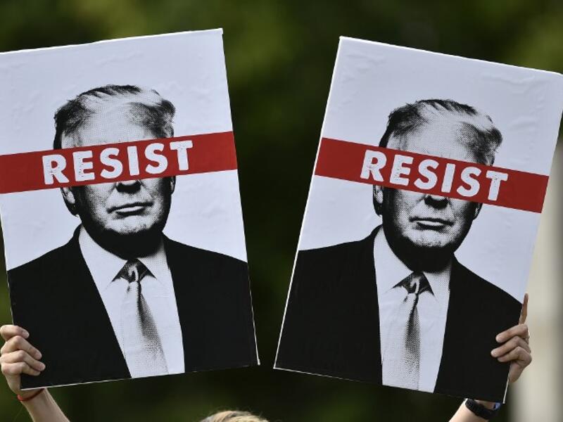 A protestor holds placards prior to the Scotland United Against Trump march through the streets of Edinburgh, Scotland on July 14, 2018, on the third day of US President Donald Trump's four-day UK visit. (NEIL HANNA / AFP)