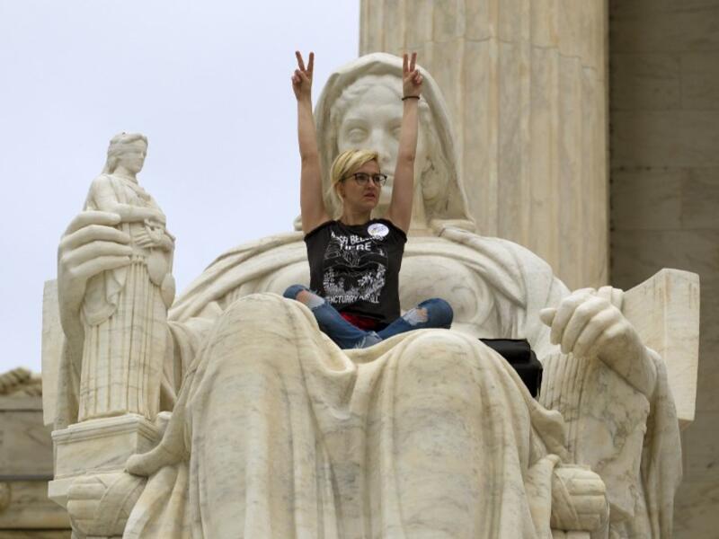 Demonstrator Jessica Campbell-Swanson of Denver, sits on the lap of the "Contemplation of Justice" statue as protestors protesting against the appointment of Supreme Court nominee Brett Kavanaugh at Capitol Hill in Washington DC, on October 6, 2018. (Jose Luis Magana / AFP)

