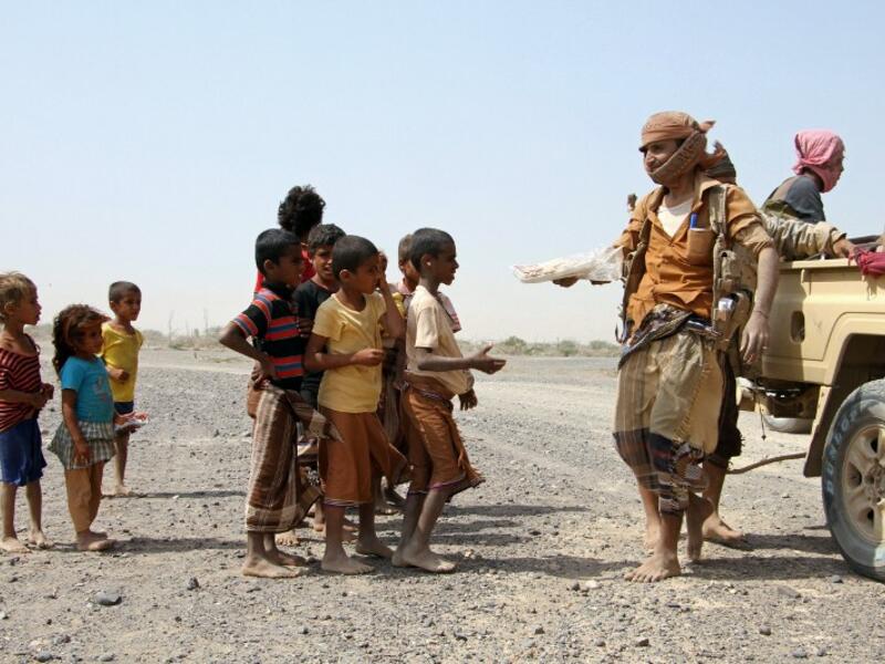 Pro-government fighters give food to Yemeni children on the road leading to the southwestern port city of Mokha on January 26, 2017. (AFP/Saleh Al Obeidi) 
