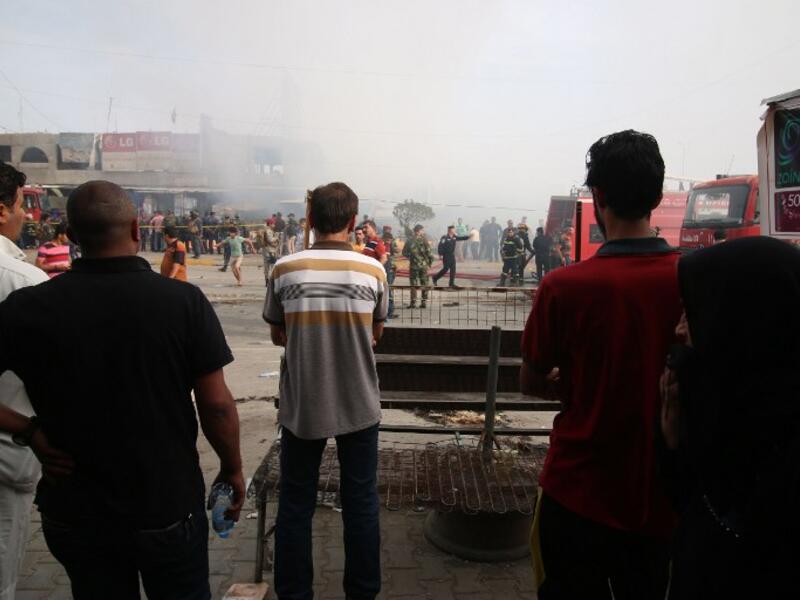 Iraqi passersby stand at the site of a suicide bombing in the Baghdad Jadida area on April 25, 2016. The blast ripped through shops in eastern Baghdad, killing at least seven people. (AFP/Haidar Mohammed Ali)