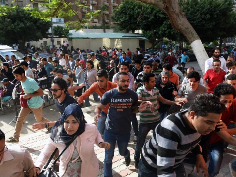 Egyptian protesters run for cover from tear gas fired by riot police during a demonstration in Cairo on April 25, 2016, against the handing over of two Red Sea islands to Saudi Arabia. (AFP/Mohamed el-Shahed)