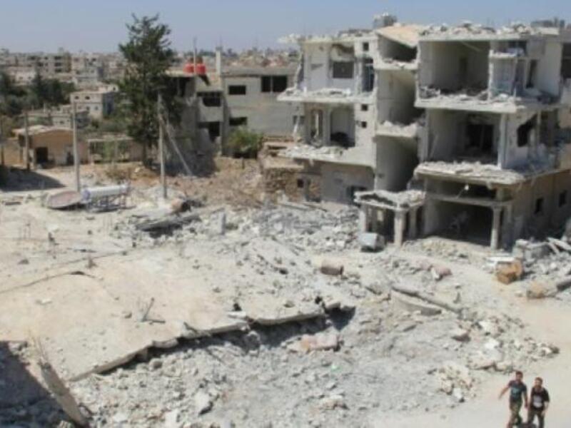 Syrian men walk past the rubble of buildings recently destroyed in airstrikes by government forces on the rebel-held neighborhood of Tareeq al-Saad in Daraa city, on August 26, 2015. (AFP/File)