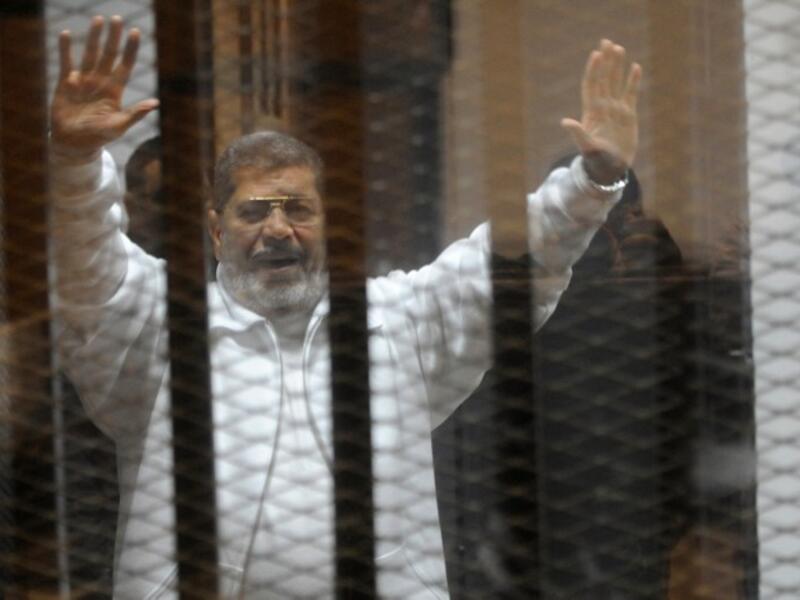 Egypt's deposed Islamist president Mohamed Morsi waves from inside the defendant’s cage during his trial at the police academy in Cairo on Jan. 8. (AFP)