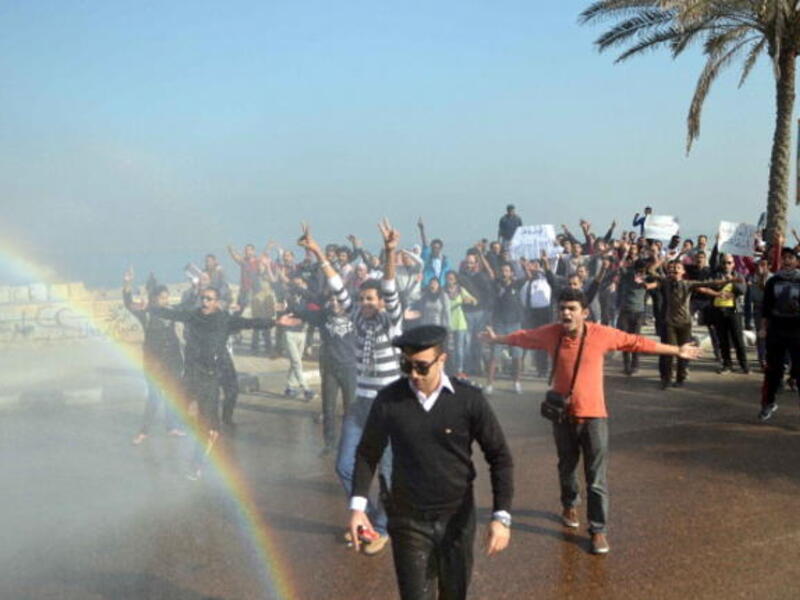Supporters of 28-year-old blogger Khaled Said who died following police questioning before the revolution in 2010, during a demonstration outside the criminal court where the second retrial session is underway on December 2, 2013. [AFP]