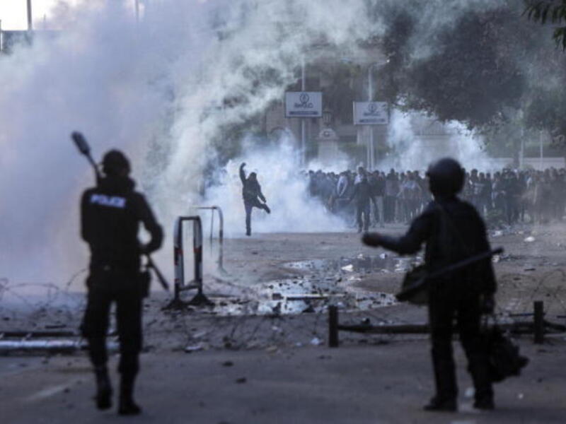 Egyptian students who support the Muslim Brotherhood (background) clash with riot policemen outside the University of Cairo campus in the capital on December 11, 2013. [AFP]