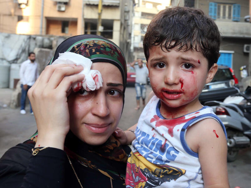 A boy and his mother are seen at the site of a car bomb between the Bir el-Abed and Roueiss neighborhoods, in the southern suburb of Beirut (AFP/STR)