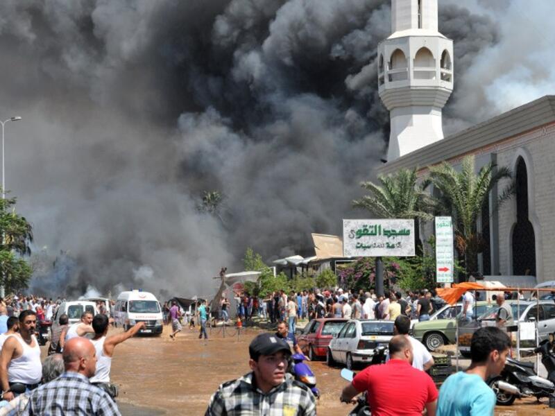 LEBANON, Tripoli : TOPSHOTS
Smoke is seen above people gathering outside a mosque on the site of a powerful explosion in the northern Lebanese city of Tripoli on August 23, 2013. AFP PHOTO IBRAHIM CHALHOUB