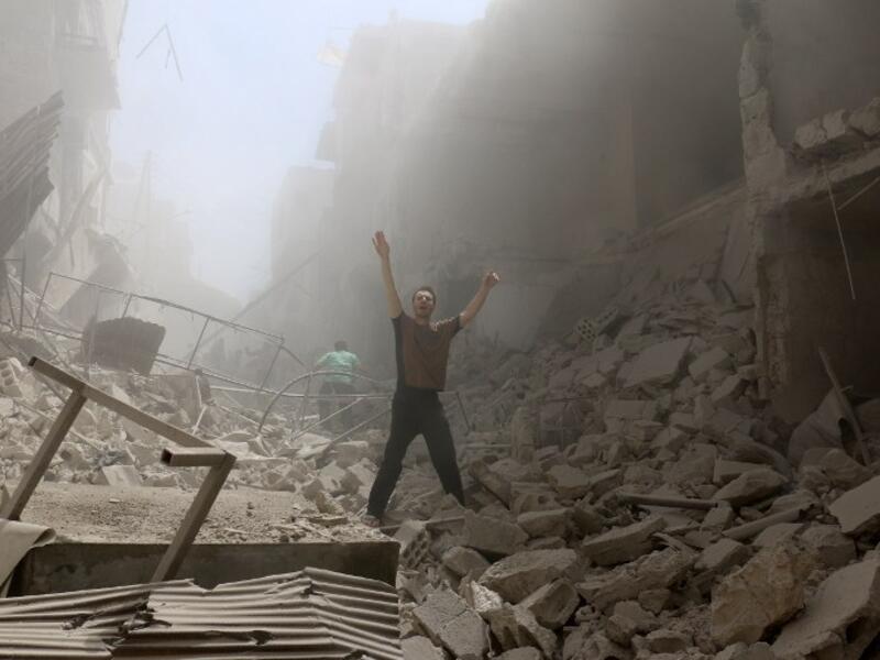 A man gestures while walking through rubble after multiple airstrikes in Aleppo today. (AFP/Amee Alhalbi)
