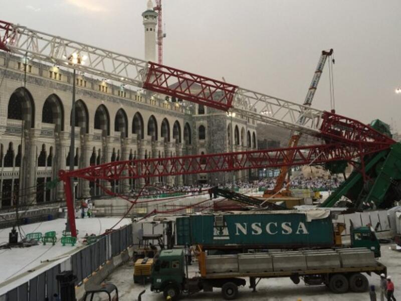 Workers stand next to the crane that collapsed the day before at the Grand Mosque on September 12, 2015. (AFP/File) 
