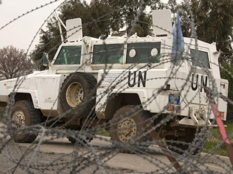 A UN vehicle is seen driving behind barbwire as UN peacekeepers leave a post, in the demilitarised United Nations Disengagement Observer Force (UNDOF) zone, in the Golan Heights. (AFP PHOTO/JACK GUEZ)