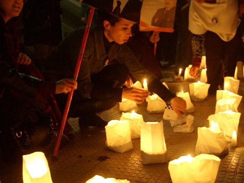 Lebanese supporters of the Mostaqbal Movement bloc light candles during a vigil as others holds pictures of former Lebanese premier Rafiq Harir and his son former prime minister Saad Hariri in the southern Lebanese city of Sidon. [AFP]