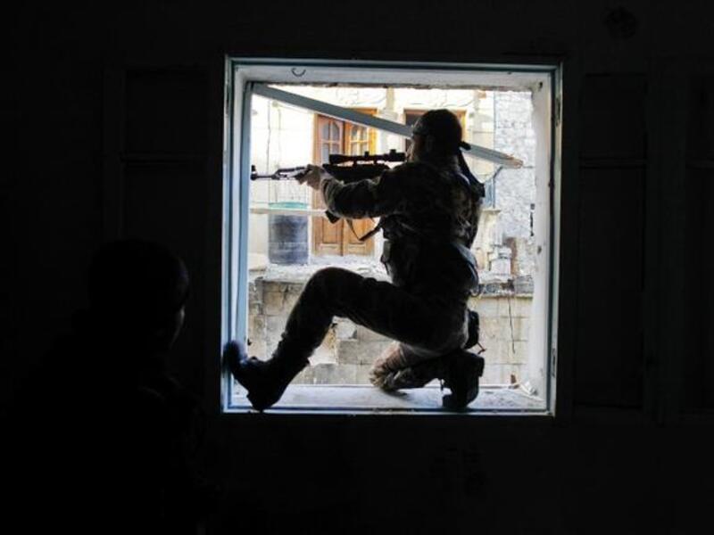 A member of Liwa (Brigade) Salahadin, a Kurdish military unit fighting along side rebel fighters, aims at a regime fighter in the besieged district of Karmel al-Jabl in eastern Aleppo. (TOPSHOTS/AFP PHOTO/JAVIER MANZANO)