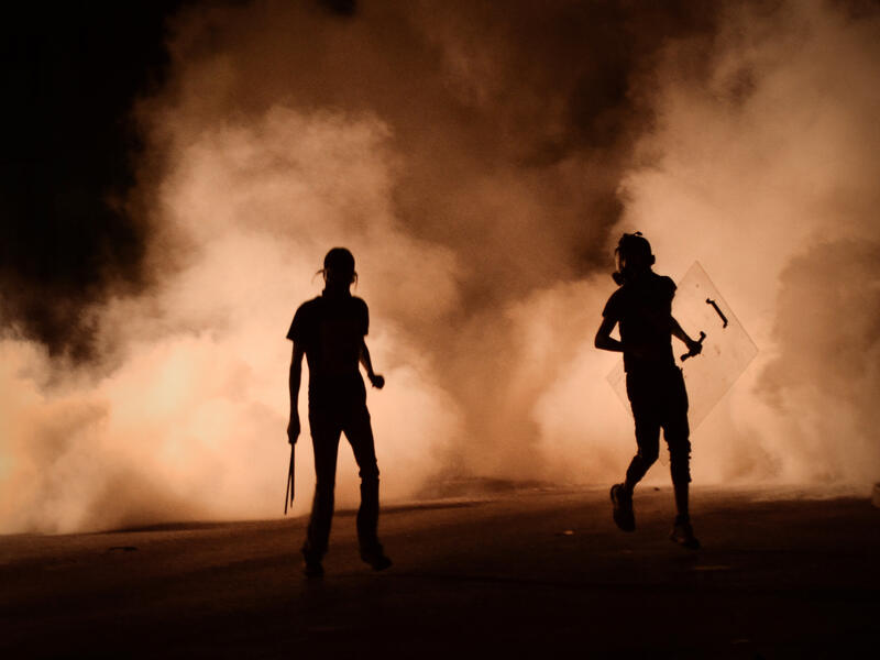 Bahraini protestors run for cover during clashes with riot police following a protest against the ruling regime (AFP/MOHAMMED AL-SHAIKH)