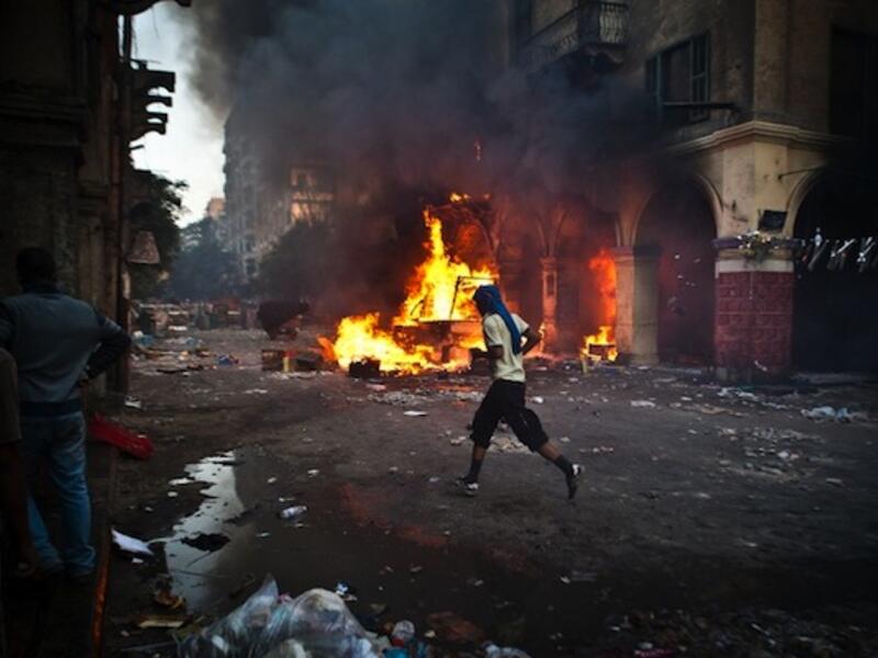 A supporter of the Muslim Brotherhood and of ousted president Mohamed Morsi runs past a burning vehicle during clashes with security officers close to Cairo's Ramses Square, on August 16, 2013. (AFP)
