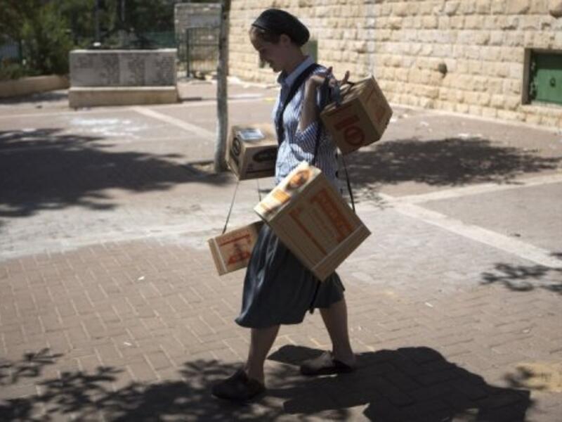 An Israeli woman carries gas masks as she leaves the distribution centre in Jerusalem on August 26, 2013 (AFP)
