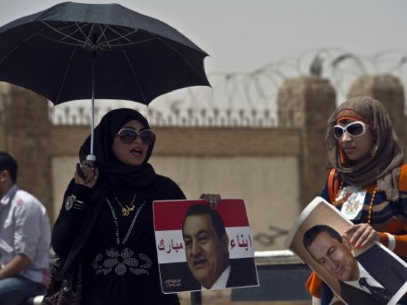 Egyptian female supporters of Egypt's former president Hosni Mubarak, hold portraits of him outside the Egyptian police academy in Cairo. AFP
