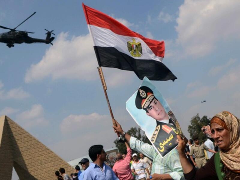Egyptians waving the national flag and a portrait of Egyptian Defence Minister and Military Chief General Abdel Fattah al-Sisi in the district of Giza, on the outskirts of Cairo, on September 20, 2013. (AFP)
