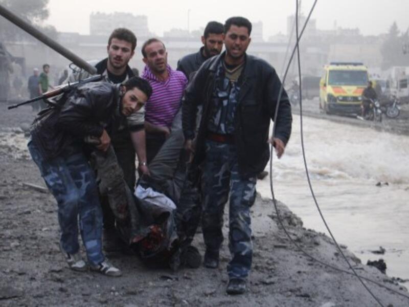 Rebels and civilians carry the body of a man killed after an air strike by pro-government forces on the Syrian city of Aleppo on November 28, 2013. (AFP)
