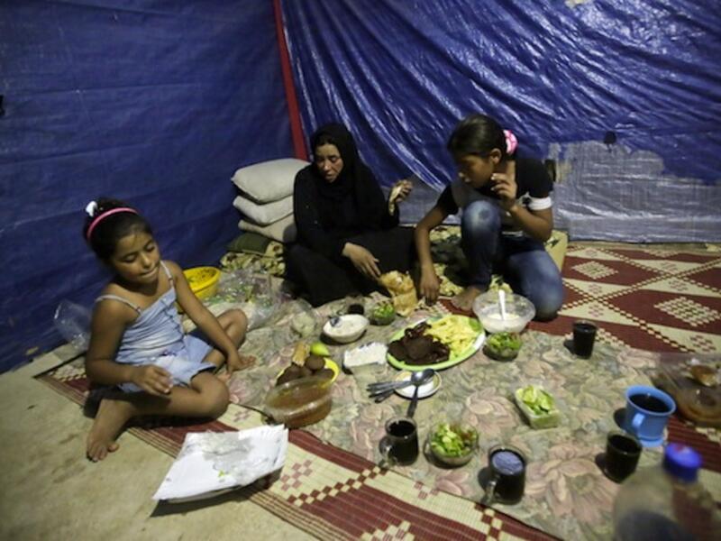 Fatima (C) a Syrian refugee widow, who lost her husband during the fighting in Homs, and her daughters have their Ramadan dinner in their makeshift room in a neighborhood of the Lebanese coastal city of Tripoli (AFP/JOSEPH EID)