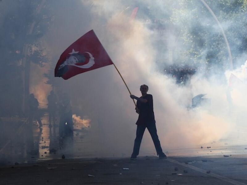 Tear gas surrounds a protestor holding a Turkish flag with a portrait of the founder of modern Turkey Mustafa Kemal Ataturk as he takes part in a demonstration in support of protests in Istanbul in Ankara on Saturday