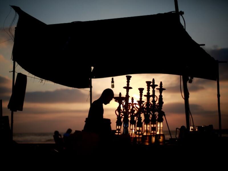 A man readies water pipes as the sun sets over the Gaza Strip during Ramadan. (AFP / Mohammed Abed)