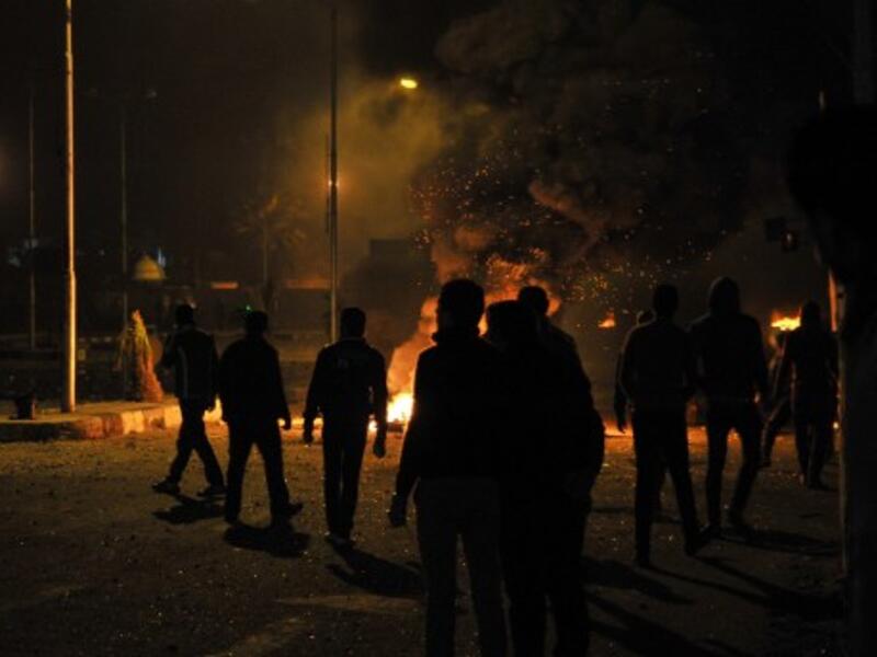Egyptian protesters stand near burning tyres outside the main security headquarters in the canal city of Port Said early on Tuesday. (Photo: AFP/STR) 
