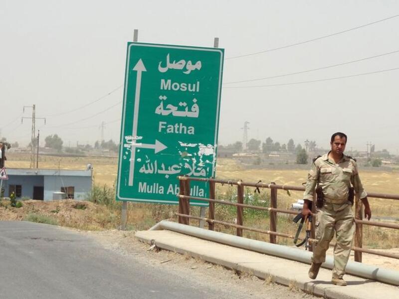An Iraqi soldier walks past a sign pointing toward Mosul. (AFP/File)