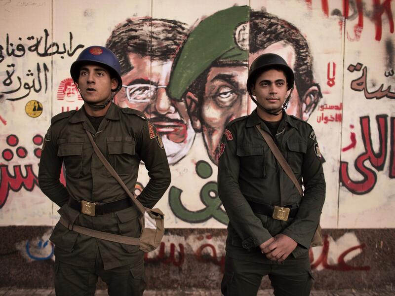 Egyptian security forces stand guard in front of satirical graffiti on the walls of the Presidential Palace in Cairo.  (AFP/File)