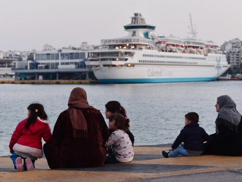 Refugee families sit on February 26, 2016 at a pier in the port of Piraeus, where hundreds of migrants and refugees, many from Syria stay temporarily. (AFP/Louisa Gouliamaki)