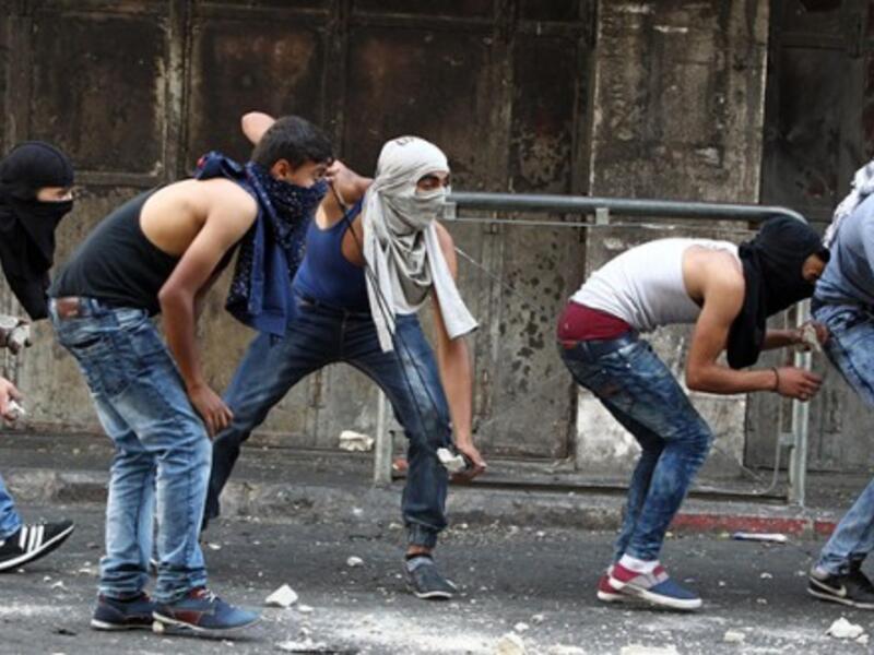 Palestinian youths throw stones towards Israeli security forces during clashes in the West Bank town of Hebron on October 4, 2015. (AFP/File)