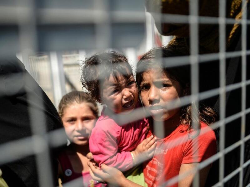 Syrian refugees wait at a Turkish border crossing to return home to the Syrian town of Tel Abyad, the scene of fierce fighting in June between Daesh and Kurdish forces.  (AFP/Bulent Kilic)