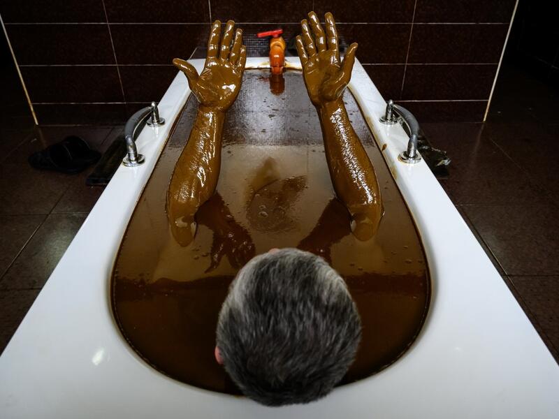 A man bathes in a tub filled with Naftalan crude oil during a treatment session at Sehirli Naftalan Health Center, some 300 kilometres (186 miles) from capital Baku, on March 21, 2019. Immersed up to her neck in crude oil, a Russian woman suffering from joint disease smiles in delight, confident that the treatment at a spa in northwestern Azerbaijan will cure her painful condition.  Mladen ANTONOV / AFP