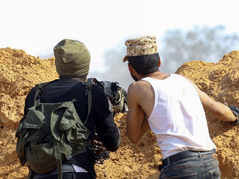 Libyan fighters loyal to the Government of National Accord (GNA) take cover behind a dirt barrier during clashes with forces loyal to strongman Khalifa Haftar south of the capital Tripoli's suburb of Ain Zara, on April 10, 2019. Mahmud TURKIA / AFP