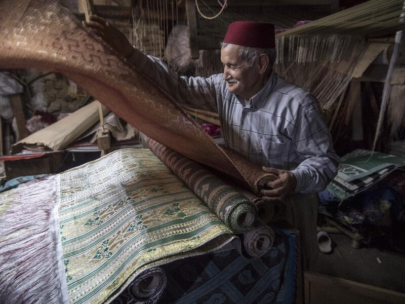 Abdelkader Ouazzani, the last of Morocco's brocade master weavers, displays tapestry at his workshop in the old city of Fez on April 10, 2019. His skilfull hands intricately create shimmering silk fabrics, enhanced with gold or silver thread, for bridal jewellery, designer creations or high-end furnishings. FADEL SENNA / AFP