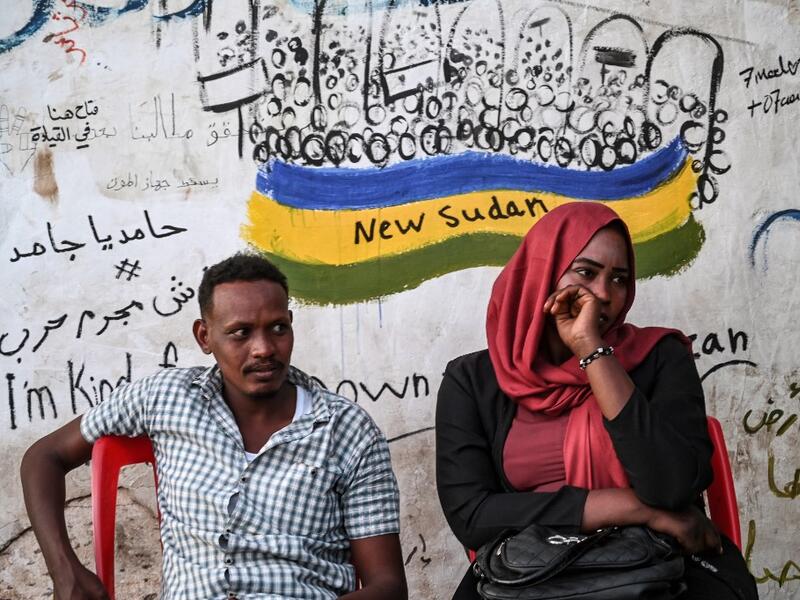 Sudanese protestors sit in front of a recently painted mural during a protest outside the army complex in the capital Khartoum OZAN KOSE / AFP