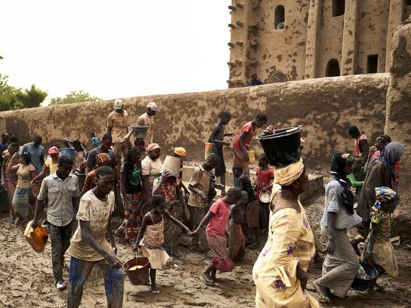 People take part in the annual rendering of the Great Mosque of Djenne in central Mali  MICHELE CATTANI / AFP