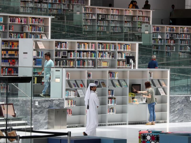 People walk through the aisles of the Qatar National Library in the capital.  KARIM JAAFAR / AFP