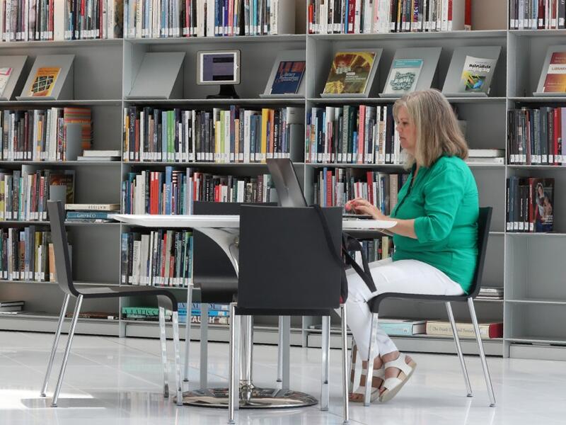 A woman works on a latpop at a table inside the Qatar National Library in the capital Doha.  KARIM JAAFAR / AFP