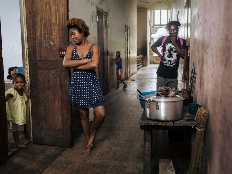 Willy, Jessica and a child, inhabitants of the roca Agostinho Neto, an abandoned cocoa plantation of Sao Tome and Principe, wait in a hall, of the hospital of the roca on May 12, 2019.  Alexis HUGUET / AFP