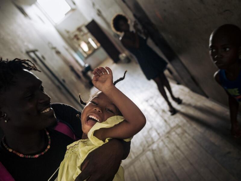 Willy, an inhabitant of the roca Agostinho Neto, an abandoned cocoa plantation of Sao Tome and Principe, plays with a child in a hall, of the hospital of the roca on May 29, 2019. Alexis HUGUET / AFP
