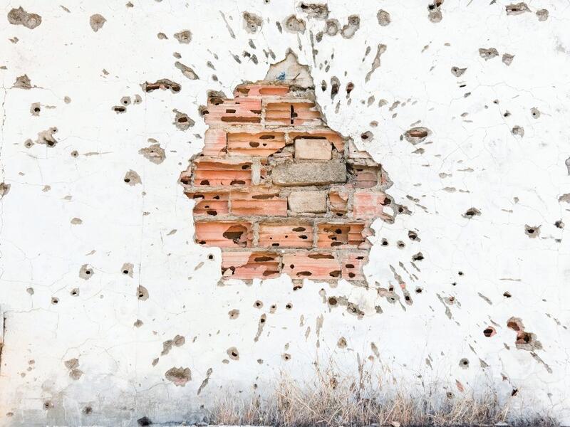 This picture shows a detail of a bullet-riddled brick wall, damaged during the Angolan civil war, in Kuito, Bie Province in Angola.  RODGER BOSCH / AFP