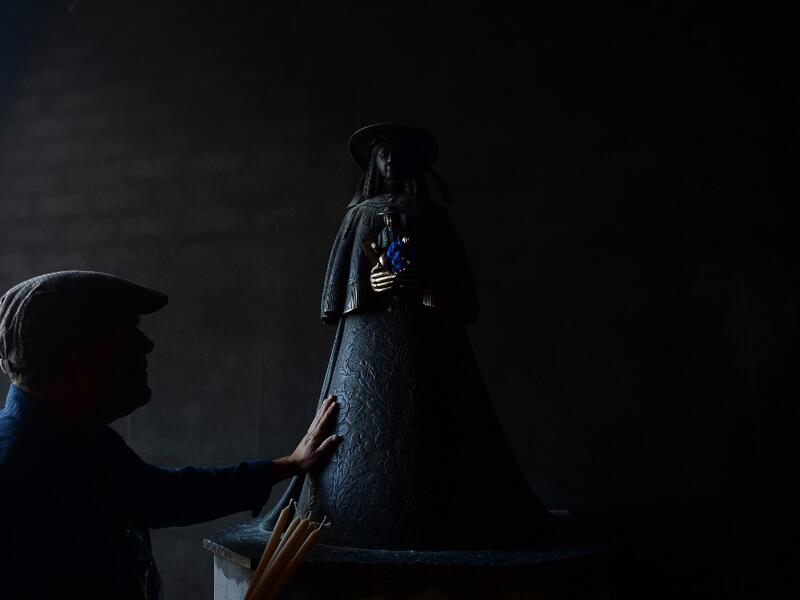 A pilgrim touches the effigy of the Rocio Virgin at the church of the village of El Rocio on June 10, 2019. CRISTINA QUICLER / AFP