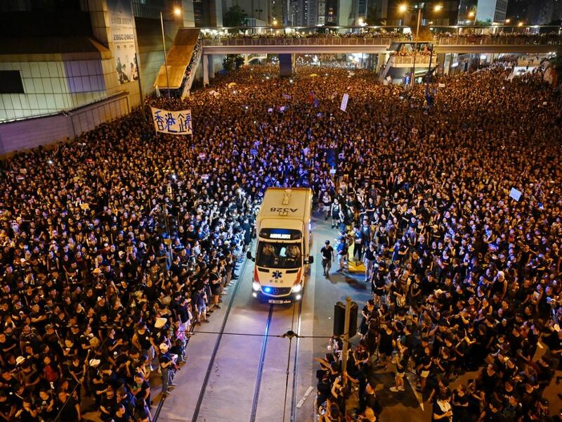 An ambulance is pictured surrounded by thousands of protesters dressed in black during a new rally against a controversial extradition law proposal in Hong Kong.  HECTOR RETAMAL / AFP