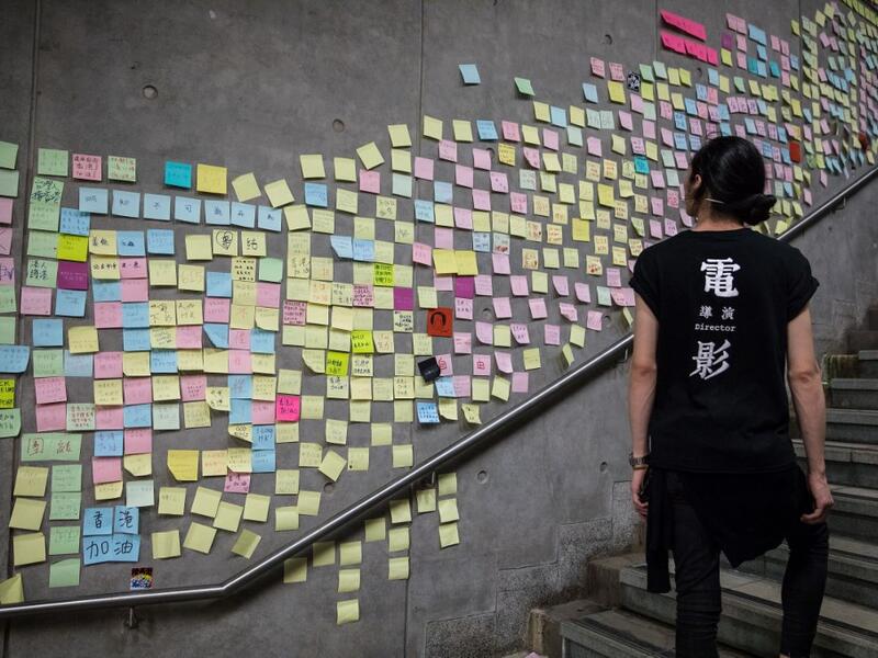 A protester looks at messages left by demonstrators outside the government headquarters after a rally against a controversial extradition law proposal in Hong Kong .  DALE DE LA REY / AFP